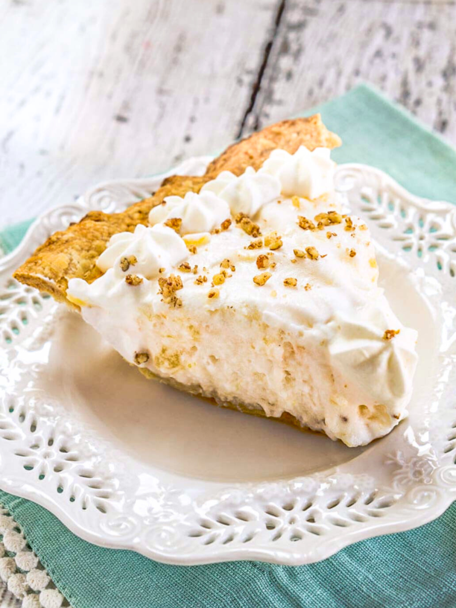 Sideview of a creamy slice of angel food pie garnished with crushed nuts and whipped cream stars - Hostess At Heart