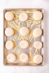 12 circles of dough sitting on a baking sheet prepared with cornmeal - Hostess At Heart