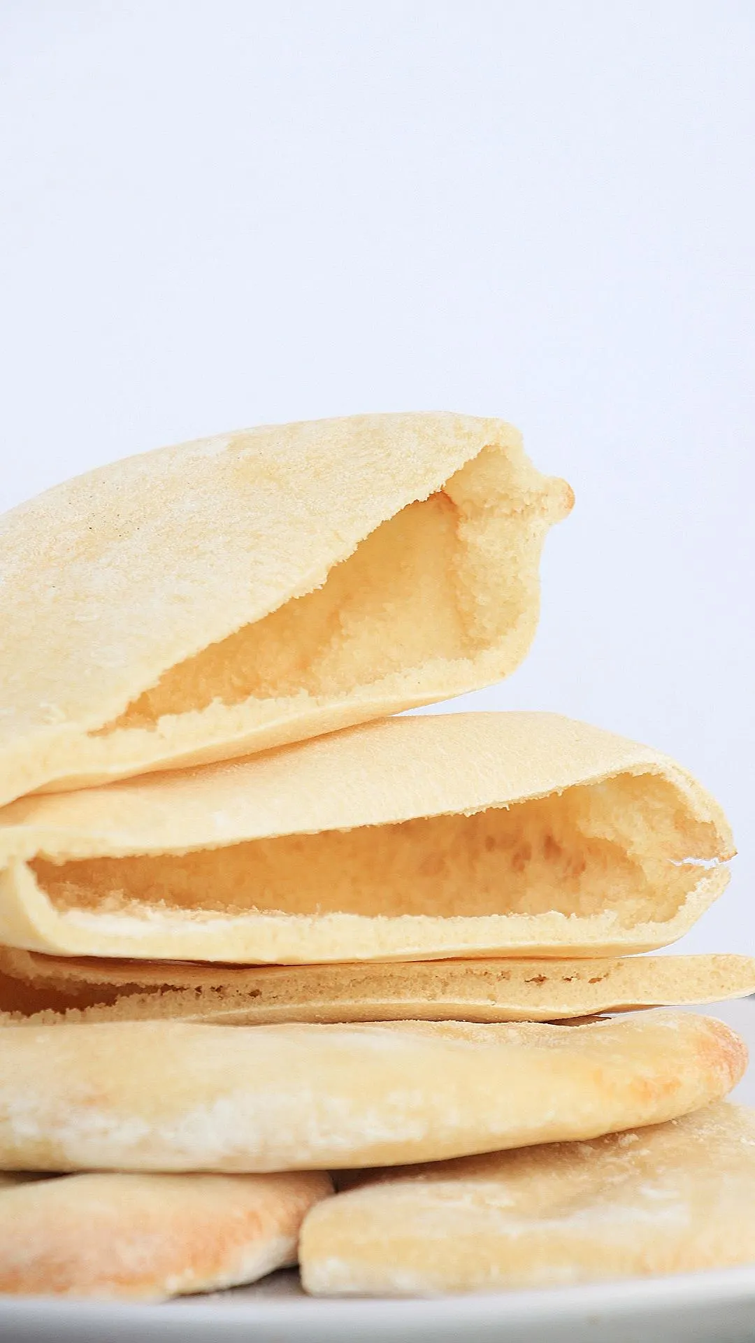 Front view of individual pieces of pita pocket bread 3 of which are sliced open and two are uncut. Hostess of Heart