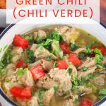 An image for Pinterest of a bowl of Pulled Pork Green Chili Verde garnished with cilantro and freshly chopped tomatoes - Hostess At Heart