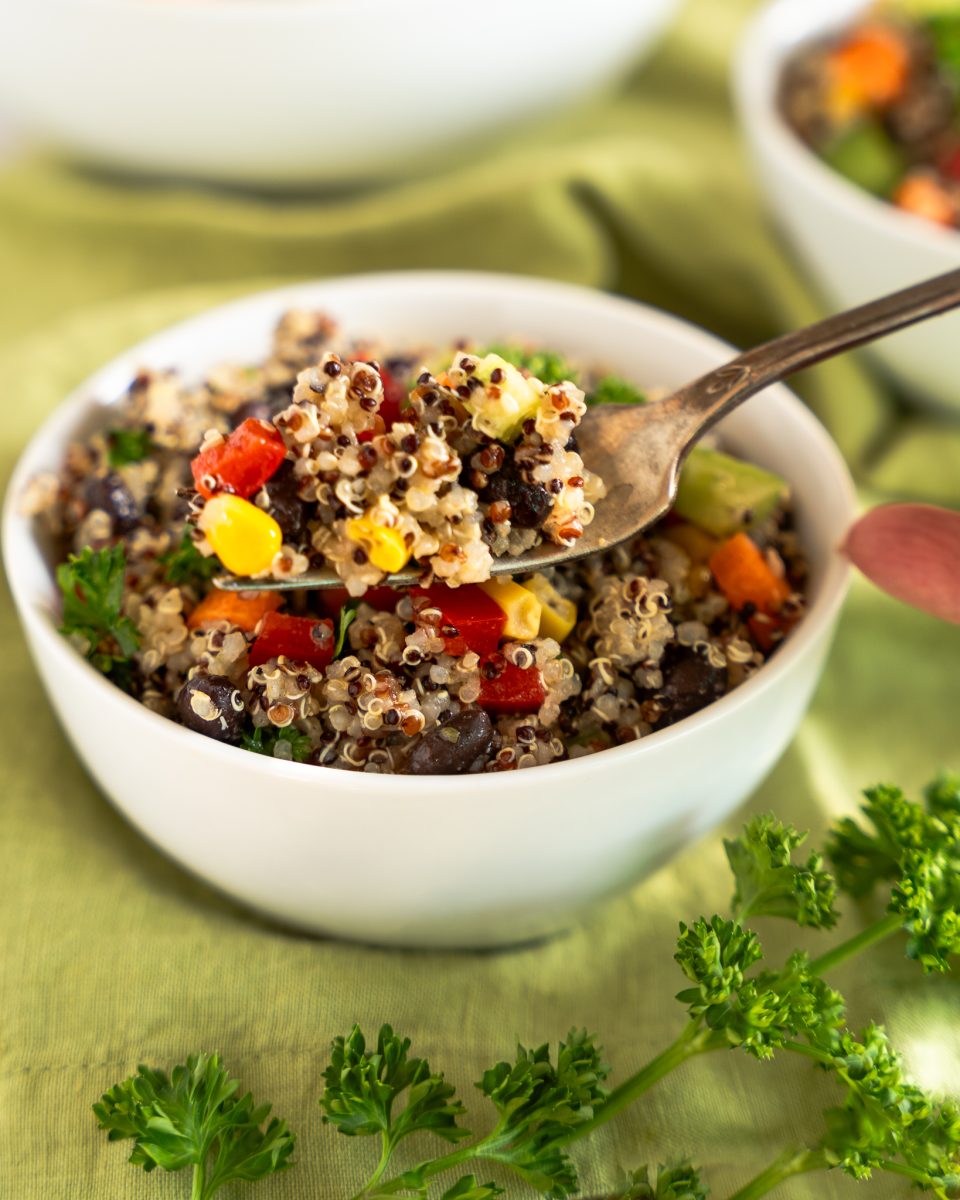 Quinoa Black Bean Salad in a white bowl with a close up of salad on a fork.