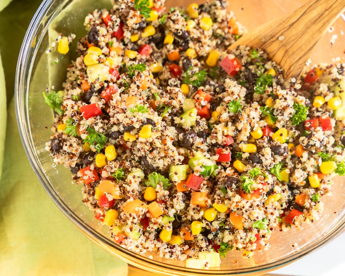 Black Bean Quinoa salad in a large mixing bowl with a wooden spoon. 