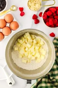 Diced butter added to dry flour ingredients in the bottom of a mixing bowl - Hostess At Heart