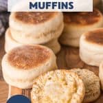 A batch of homemade Sourdough English Muffins sitting on a cutting board. The from english muffin is split in half and buttered. Hostess At Heart