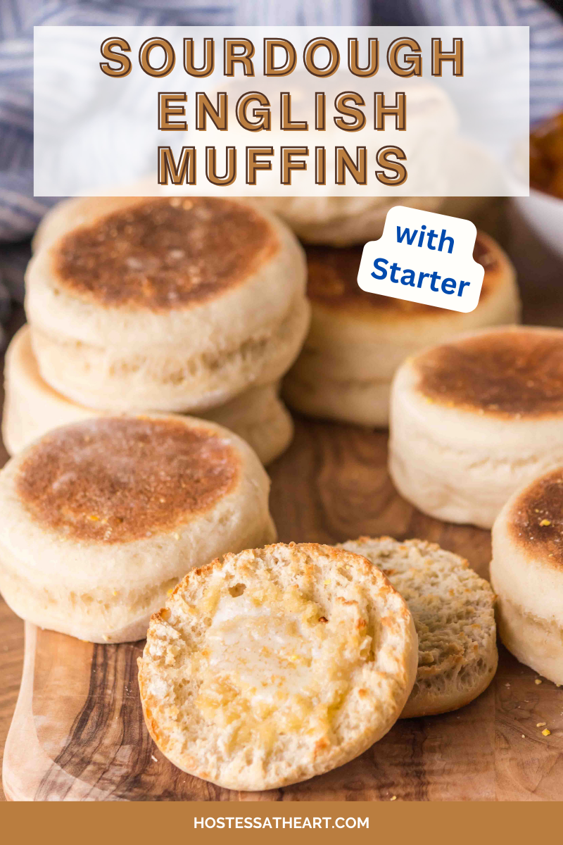 An image for Pinterest of baked golden brown sourdough english muffins sitting on a cutting board with one muffin split in half dripping with melted butter. Hostess At Heart