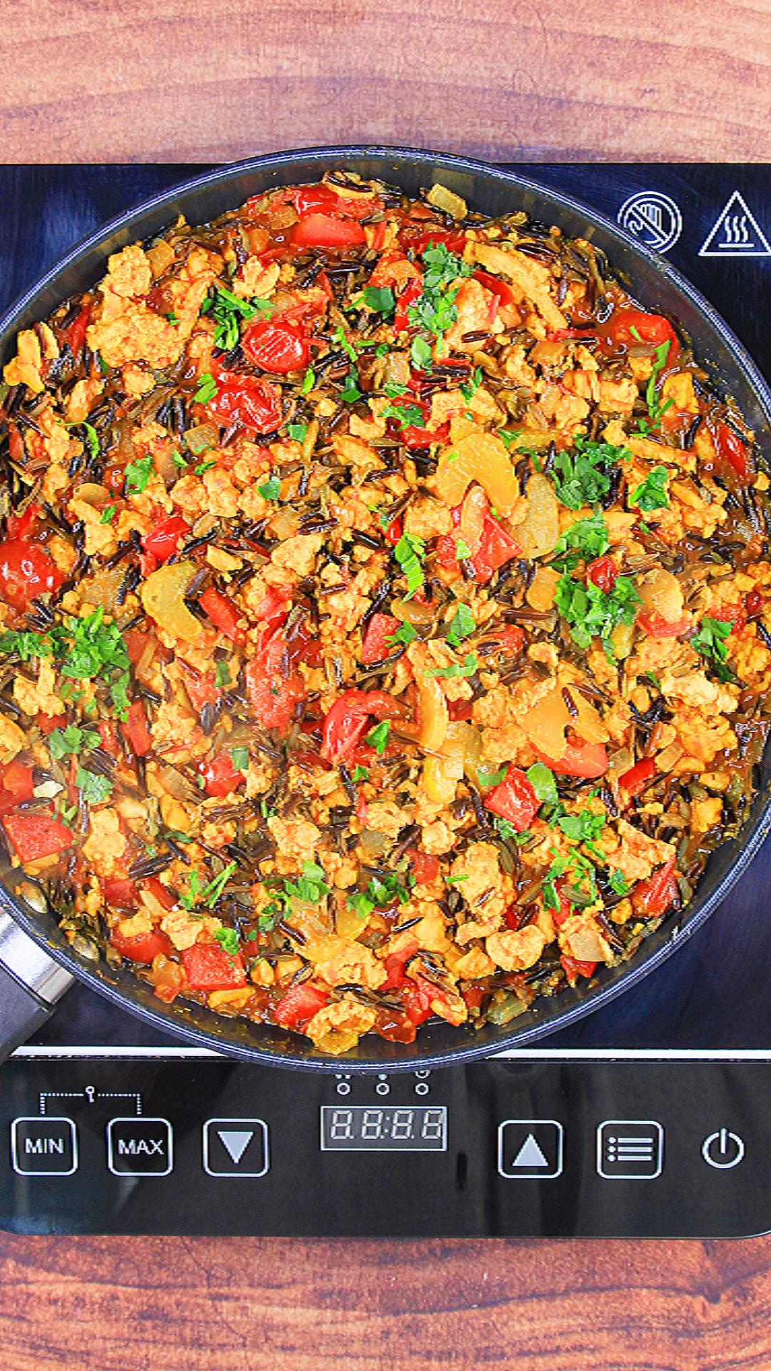 Top down view of a skillet filled with cooked turmeric ground chicken and wild rice garnished with parsley - Hostess At Heart