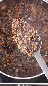 A spoon filled with cooked wild rice - hostess at heart