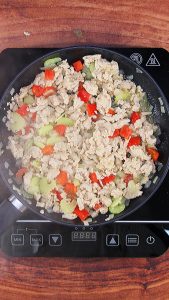 A skillet of cooked ground chicken with fresh celery, red pepper and onions.