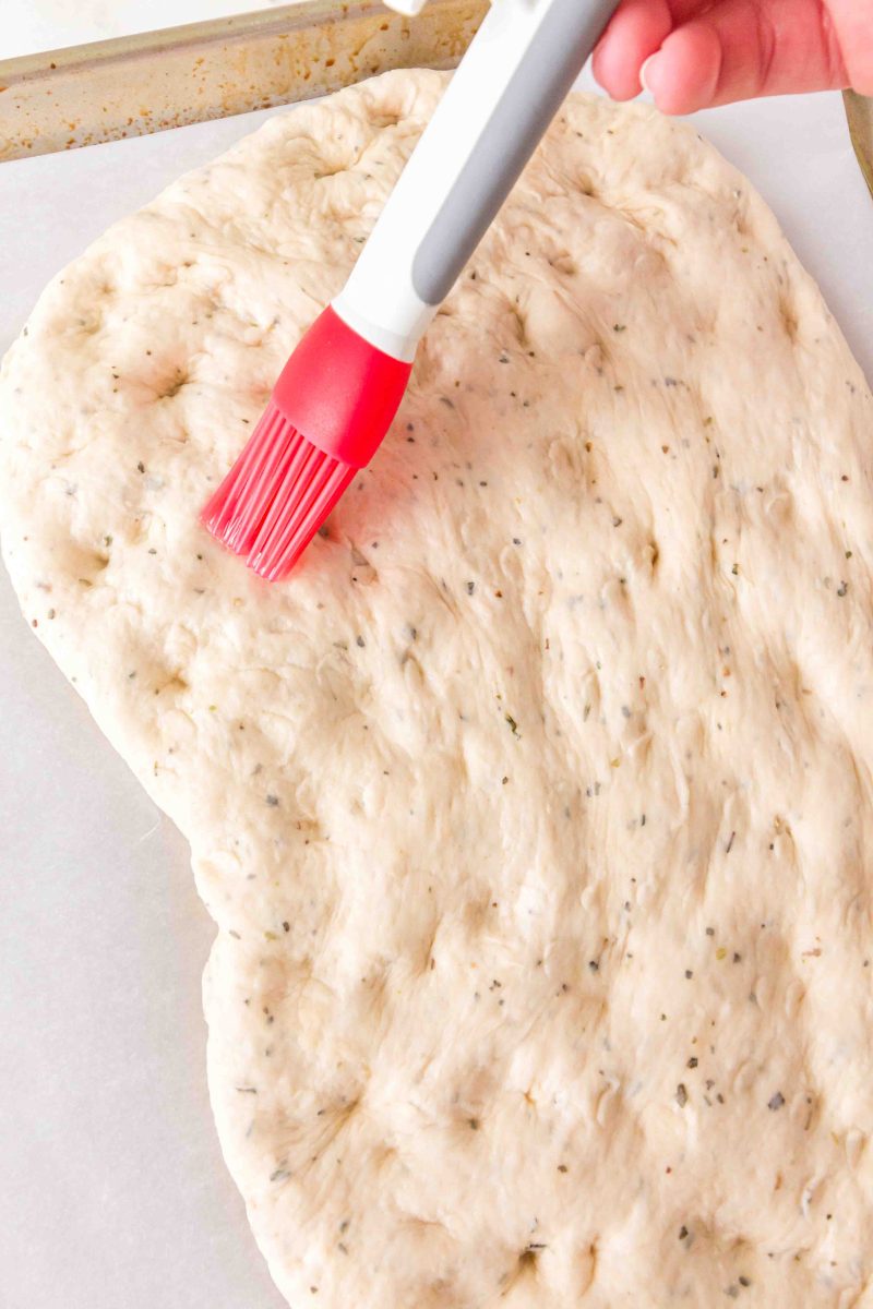 Brushing the crust with olive oil.