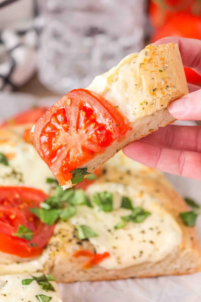 A slice of Italian flat bread pizza topped with melted cheese and a juicy slice of tomato. Hostess At Heart