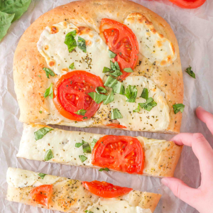 Top down view of a slice flatbread Margherita Pizza topped with sweet basil and fresh tomatoes with mozzarella cheese. Hostess At Heart