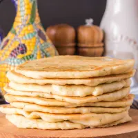 Sideview of a stack of homemade flatbread sitting on a cutting board with an olive oil caraffe in the back. HostessAtHeart.com