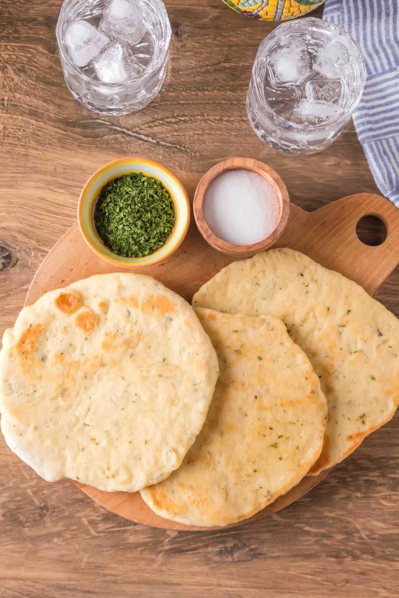 Top down view of a cutting board with flatbreads on top.