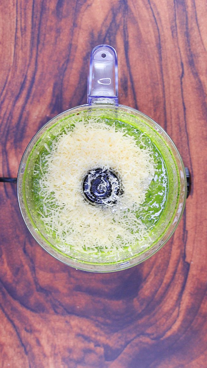 Grated Parmesan cheese added to a food processor filled with pesto ingredients. Hostess At Heart