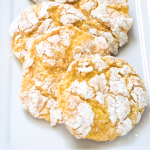 Front table view of yellow Lemon Cake Mix Cookies layered in a row on a white plate. Hostess At Heart