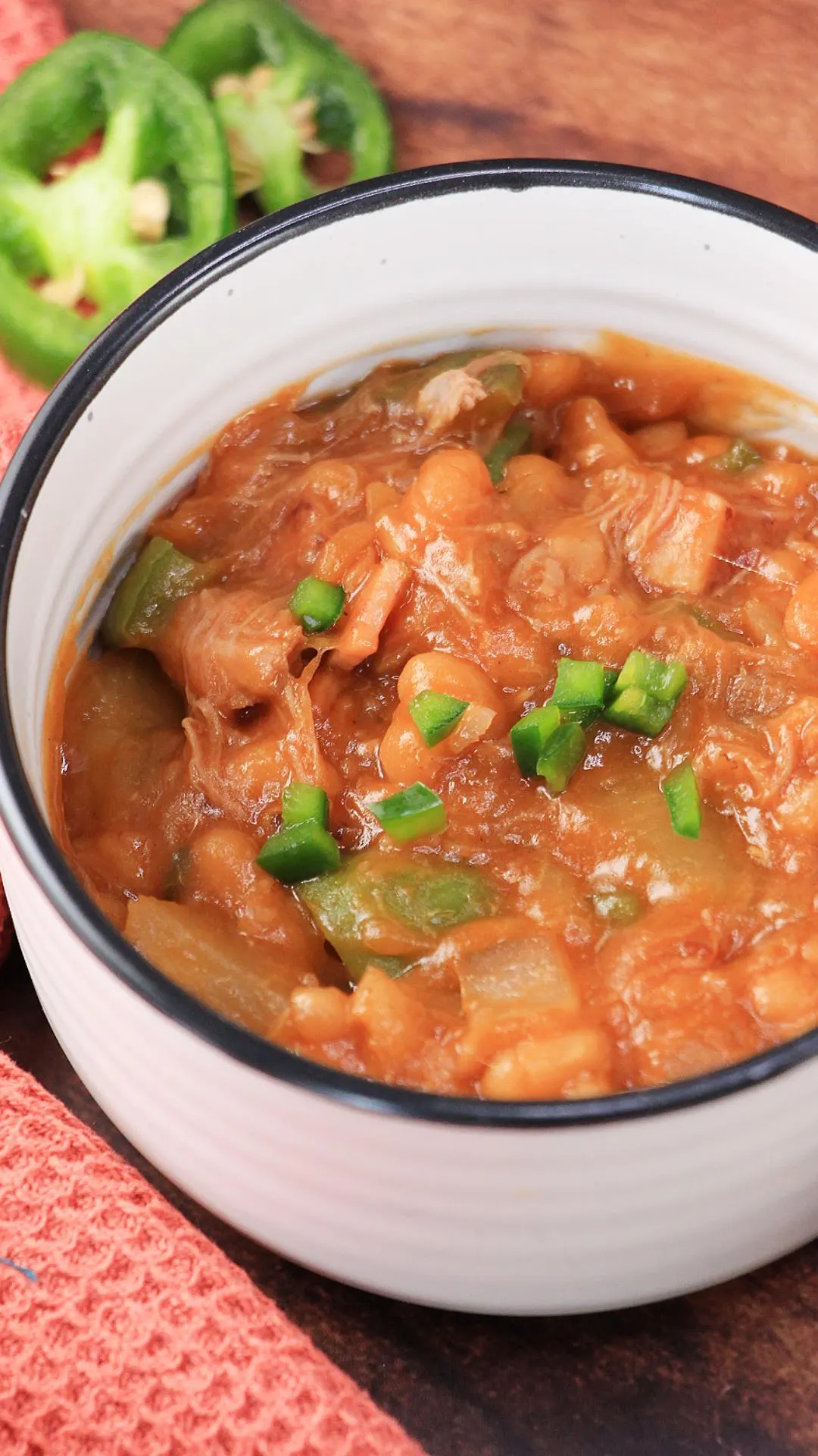 A white bowl filled with baked beans topped with diced jalapenos. Hostess At Heart