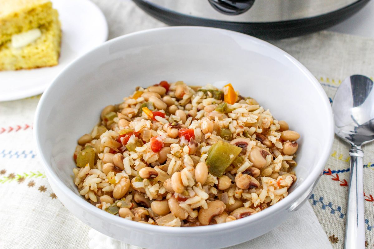 A large bowl filled with cooked rice with black eyed peas and vegetables.