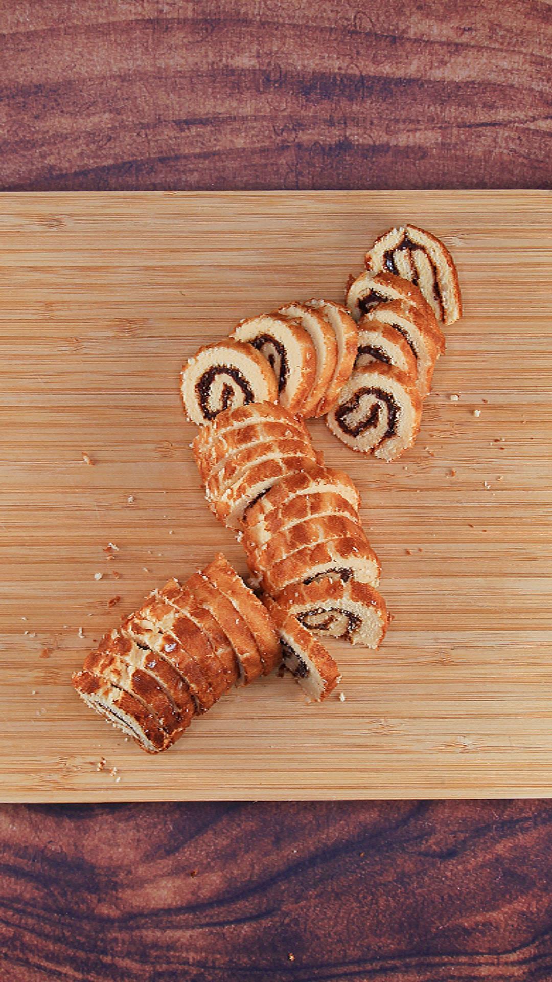 Cutting board topped with slices of cake swirled with butter cream