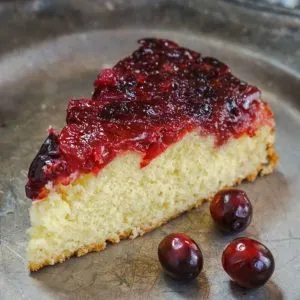 Sideview of a slice of buttery cake topped with a bright red cranberry topping - Hostess At Heart