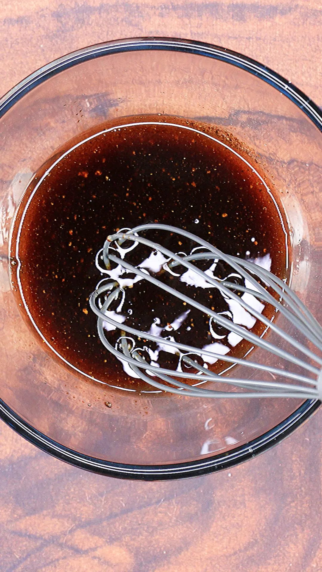 Homemade Balsamic Dressing in a large mixing bowl with a whisk hovering.