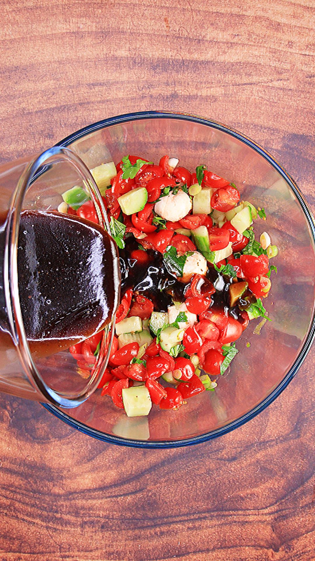 Pouring homemade balsamic viniagrette over the tomato mozzarella salad.