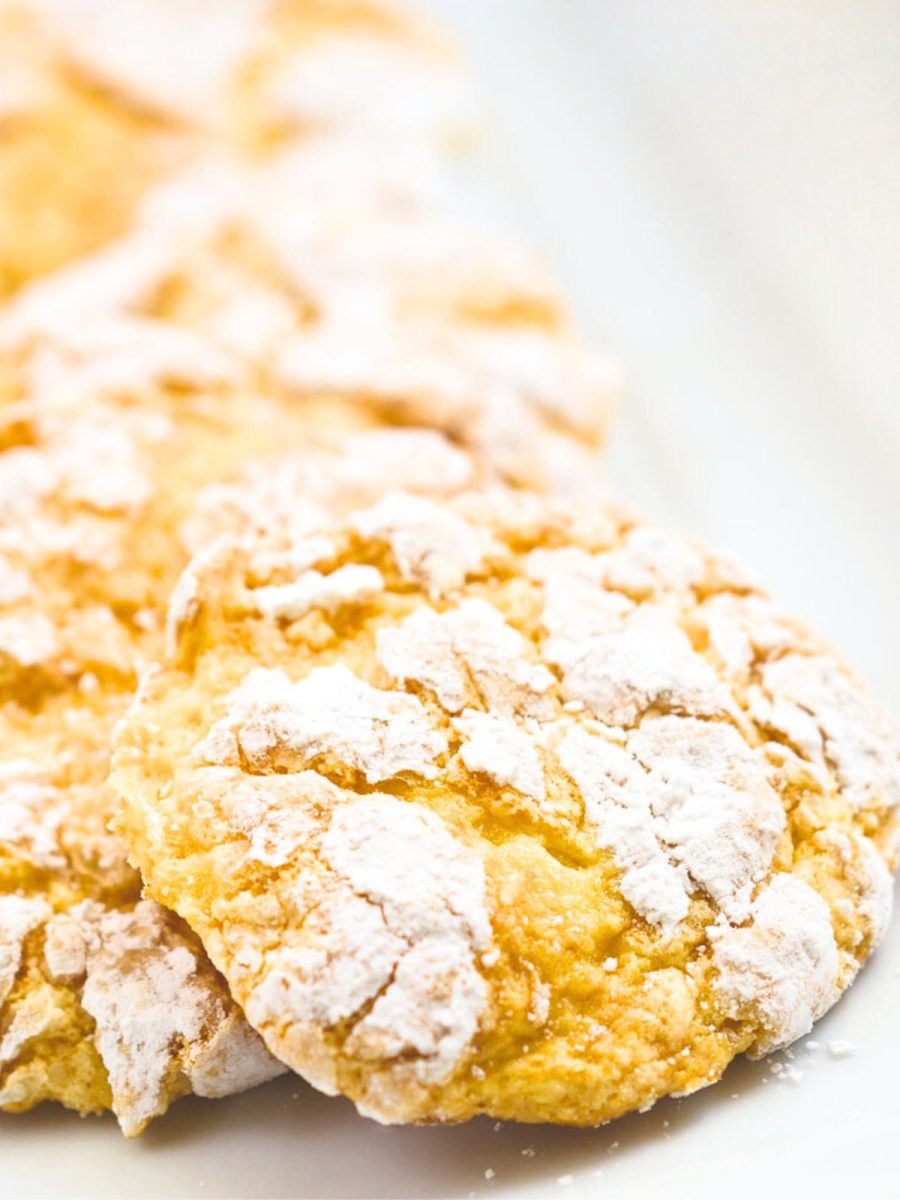 Front table view of yellow Lemon Snowflake cookies layered in a row on a white plate. Hostess At Heart