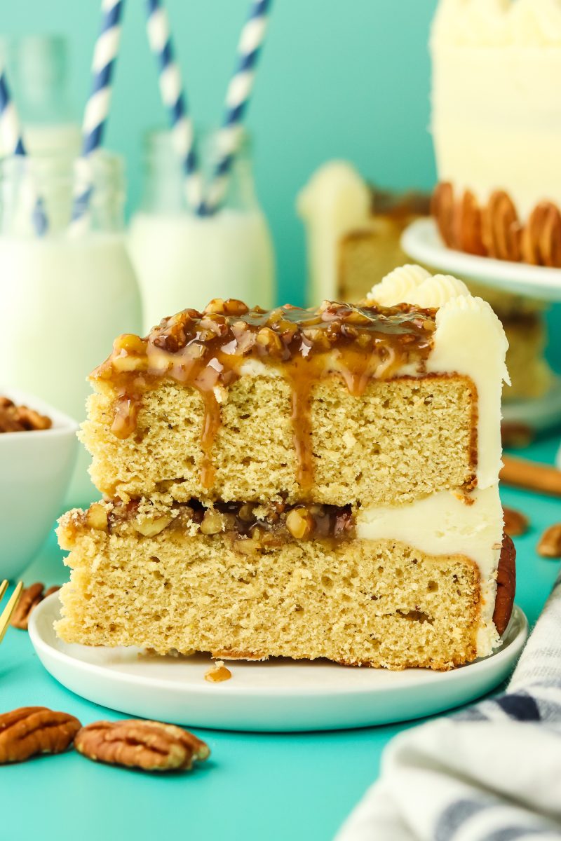 A sideview of a slice of layered cake filled with pecan pie filling and frosted with buttercream.