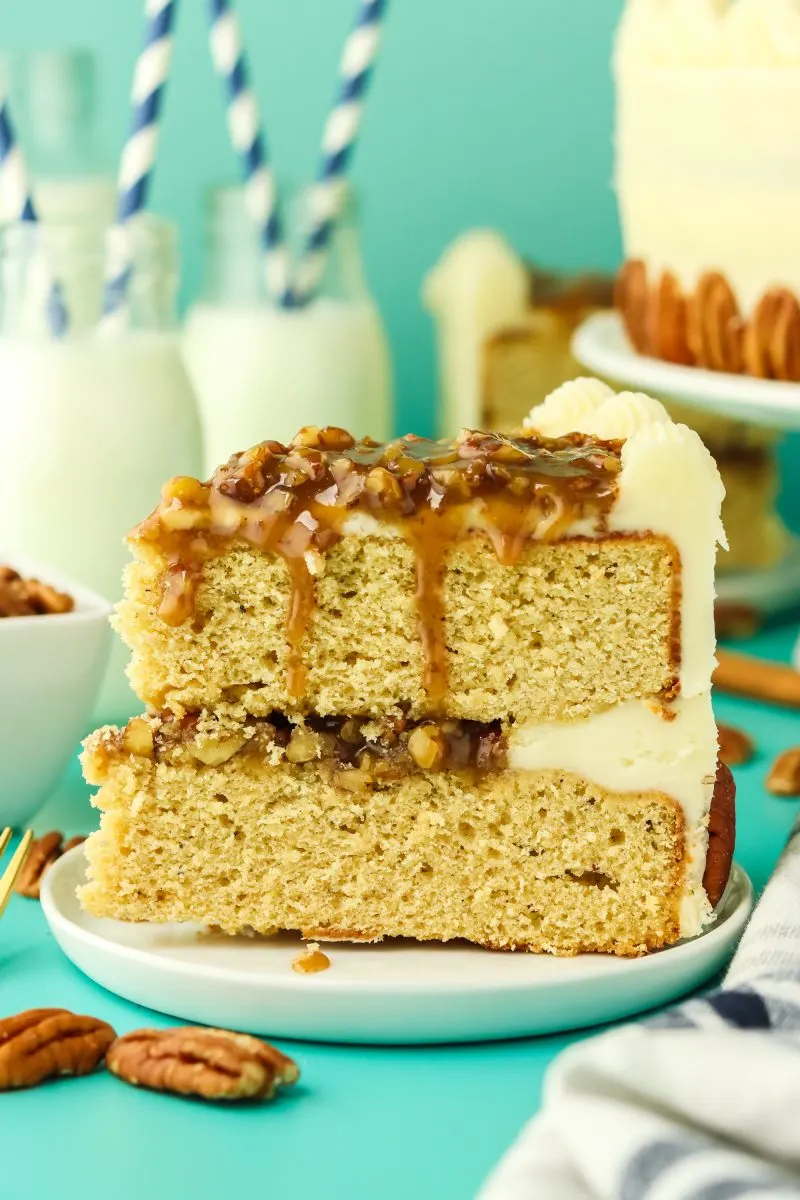 A sideview of a slice of layered cake filled with pecan pie filling and frosted with buttercream.