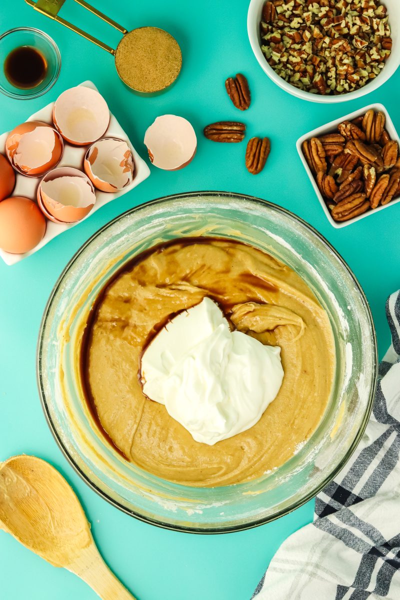 Top down view of sour cream and vanilla extract added to cake batter in a mixing bowl. Hostess At Heart