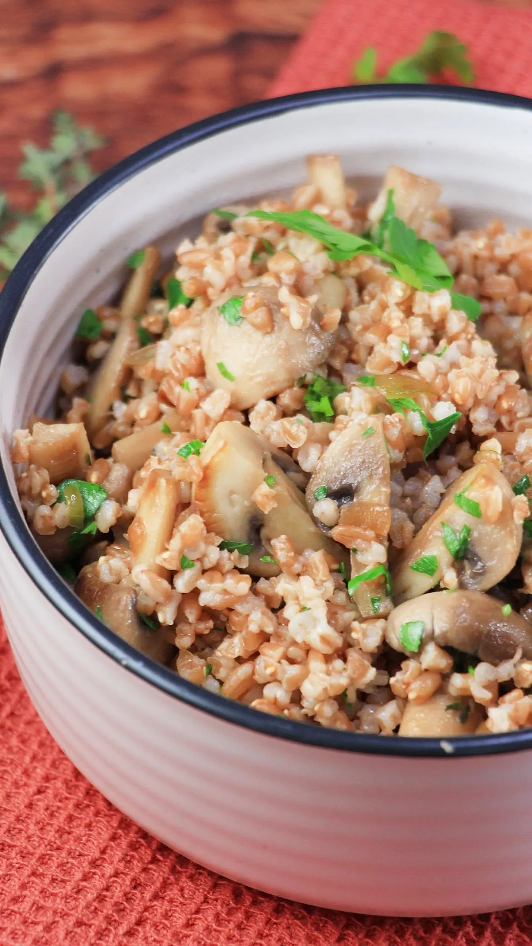 Angled view of a bowl filled with a mixture of mushrooms and farro garnished with parsely - Hostess At Heart