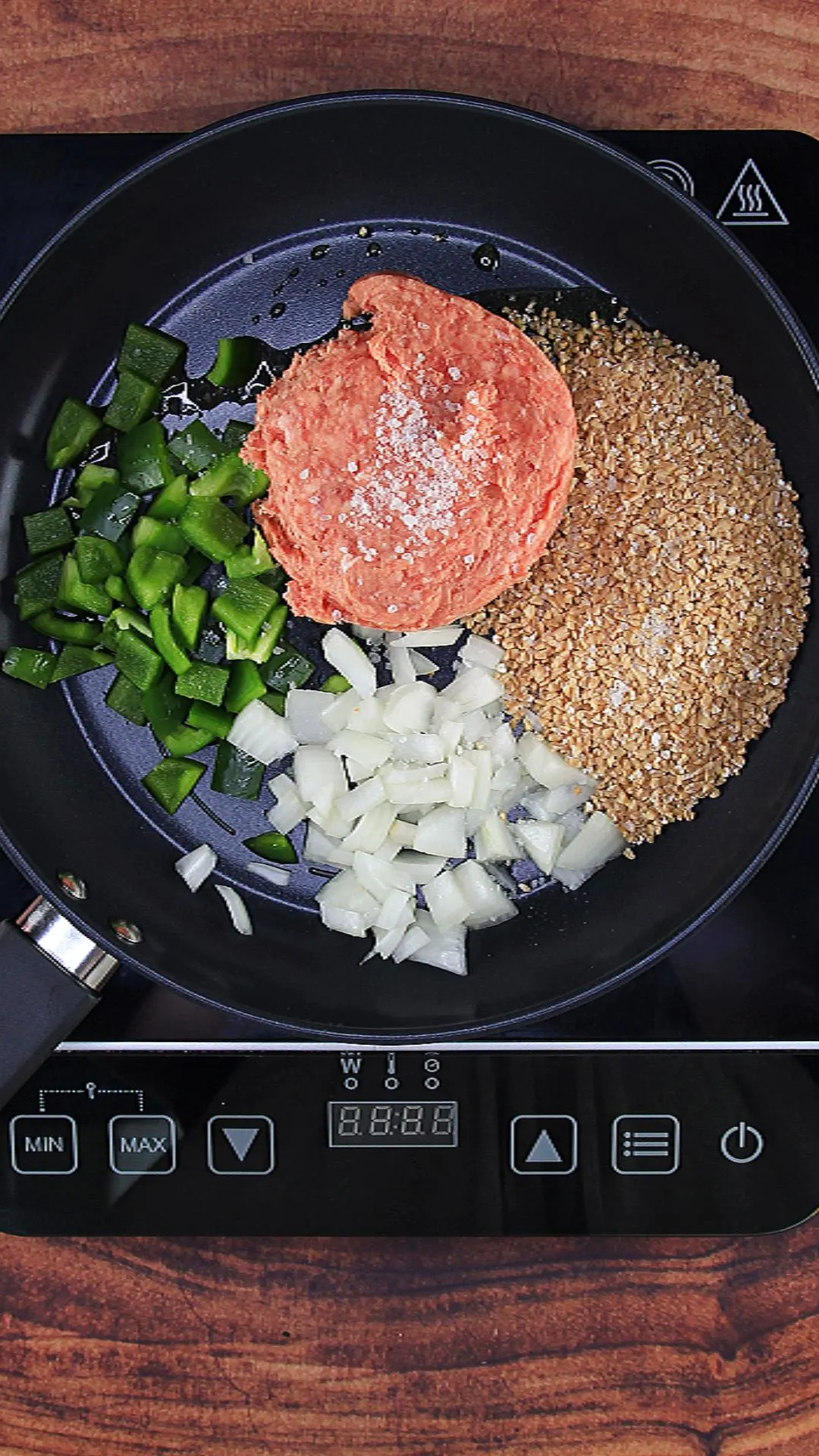 Sausage, bulgur wheat, green pepper, and onion sauteeing in a skillet.