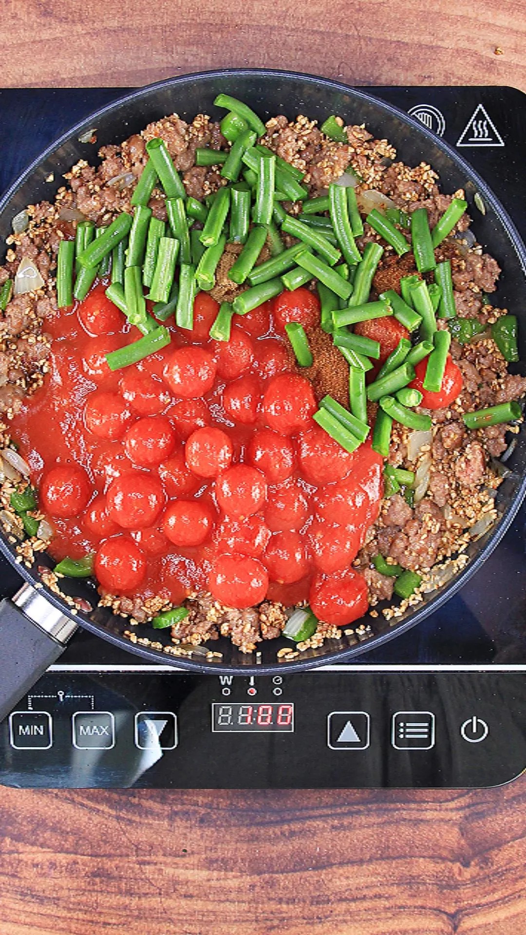 Sausage bulghur wheat in a pan with green beans and tomatoes on top.