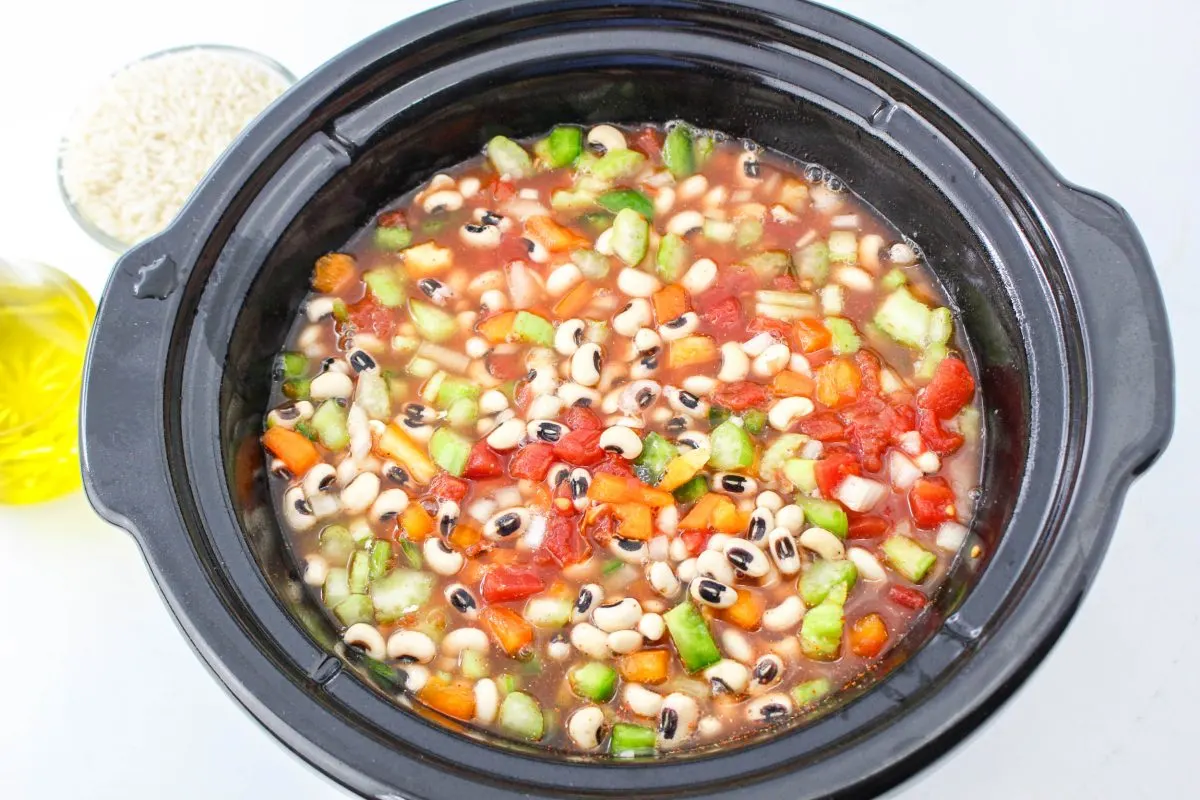 A slow cooker filled with the ingredients used to make blackeye peas with rice - Hostess At Heart