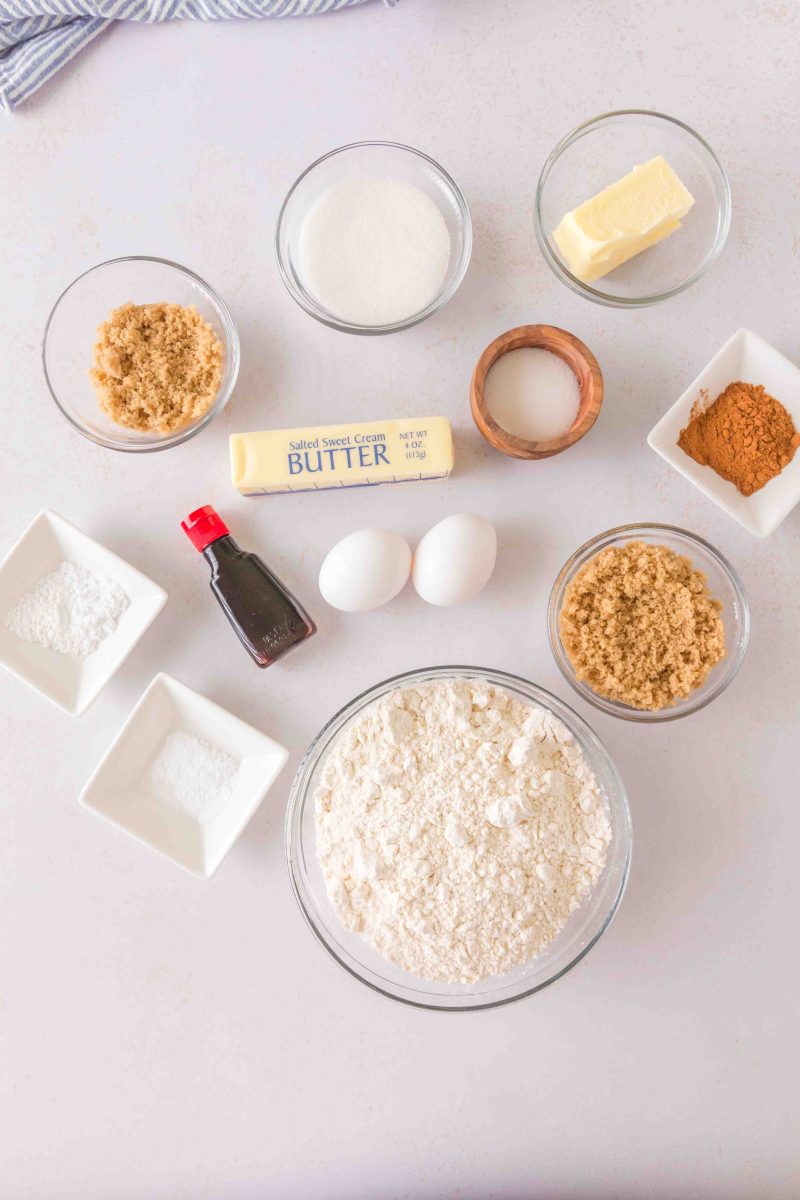 All of the ingredients for cinnamon cookies. Flour, sugar, eggs, vanilla, cinnamon, baking soda, baking powder, cream of tartar, butter, brown sugar, salt, 