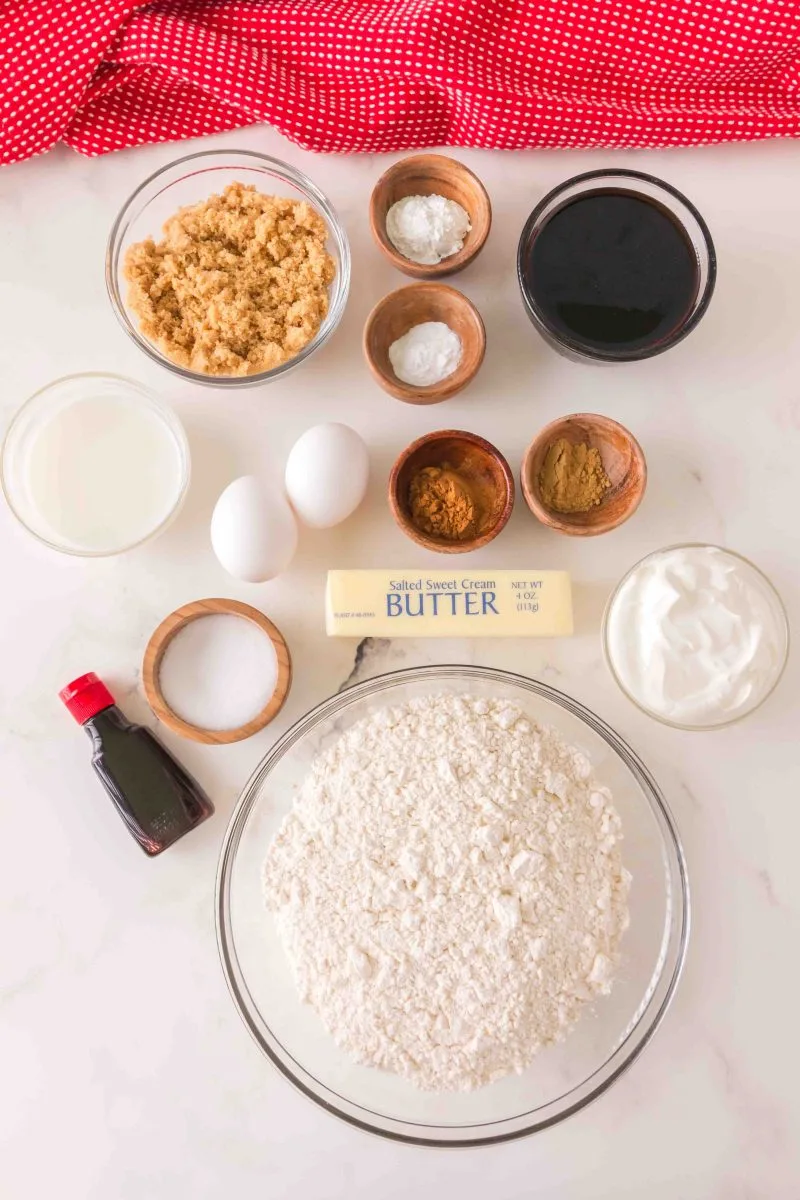 Top down image showing all of the ingredients: brown sugar, baking powder, baking soda, molasses, milk, eggs, cinnamon, ginger, sugar, butter, salt, Sour cream, vanilla, and flour.