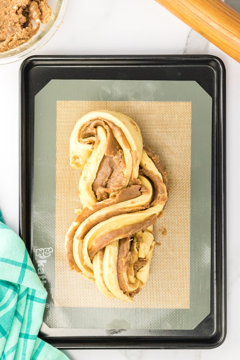 Shaped homemade cinnamom roll twist bread sitting on a baking sheet.