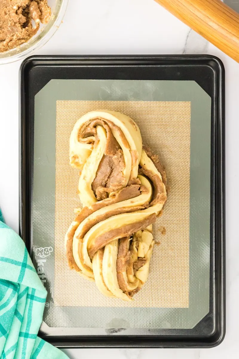 Shaped homemade cinnamom roll twist bread sitting on a baking sheet.