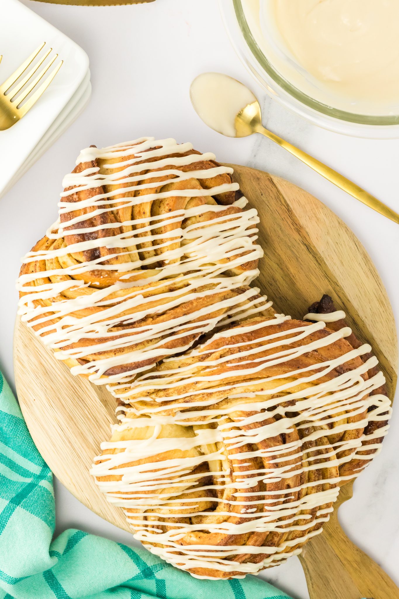 Top down view of a loaf of twisted cinnamon roll bread drizzled with glaze Hostess At Heart