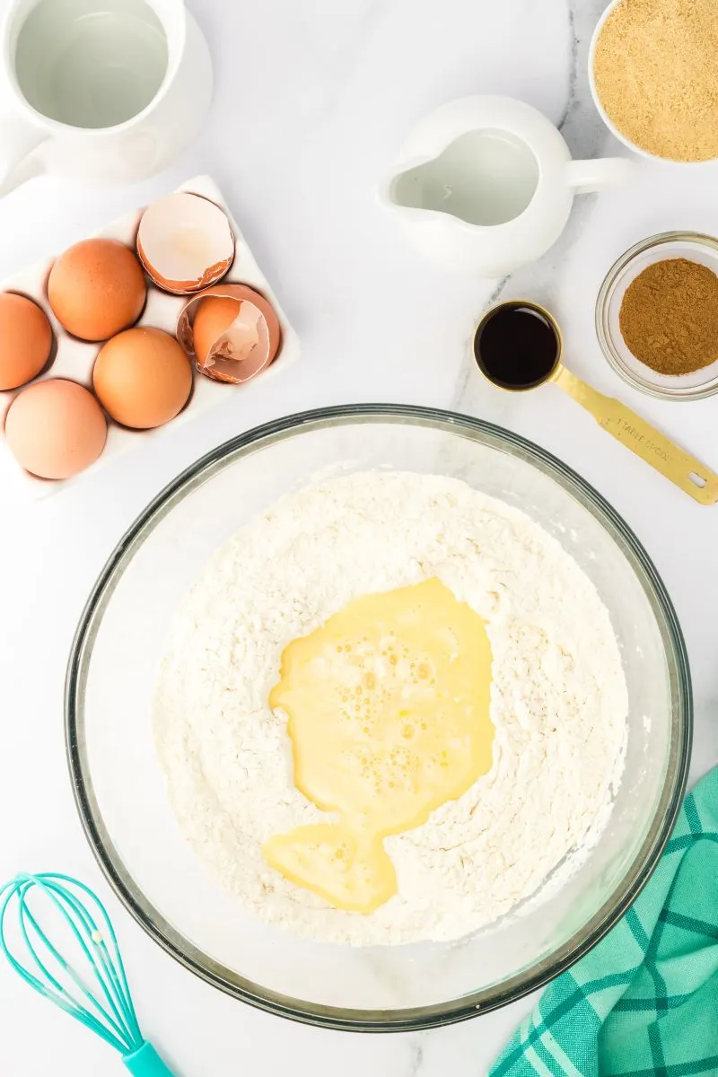 Mixing bowl filled with a flour mixture with a well in the center containing an egg mixture - Hostess At Heart