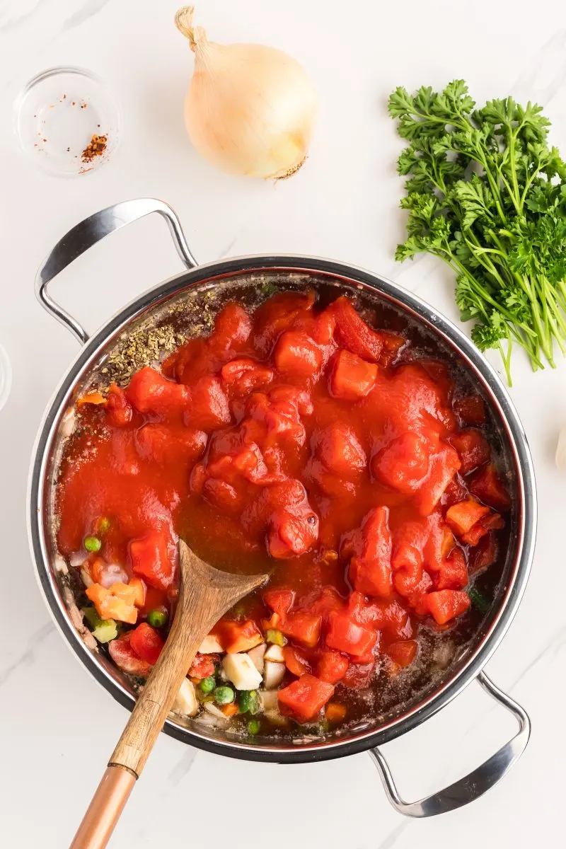 A saucepan filled with cooked ground beef, spices, veggies, and canned tomatoes. Hostess At Heart