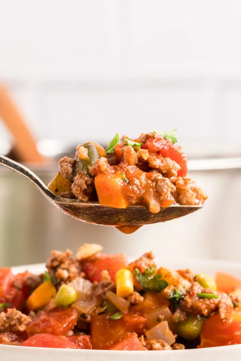 Very close zoom in on a spoonful of hamburger vegetable soup, hovering over a bowl full. Hostess At Heart