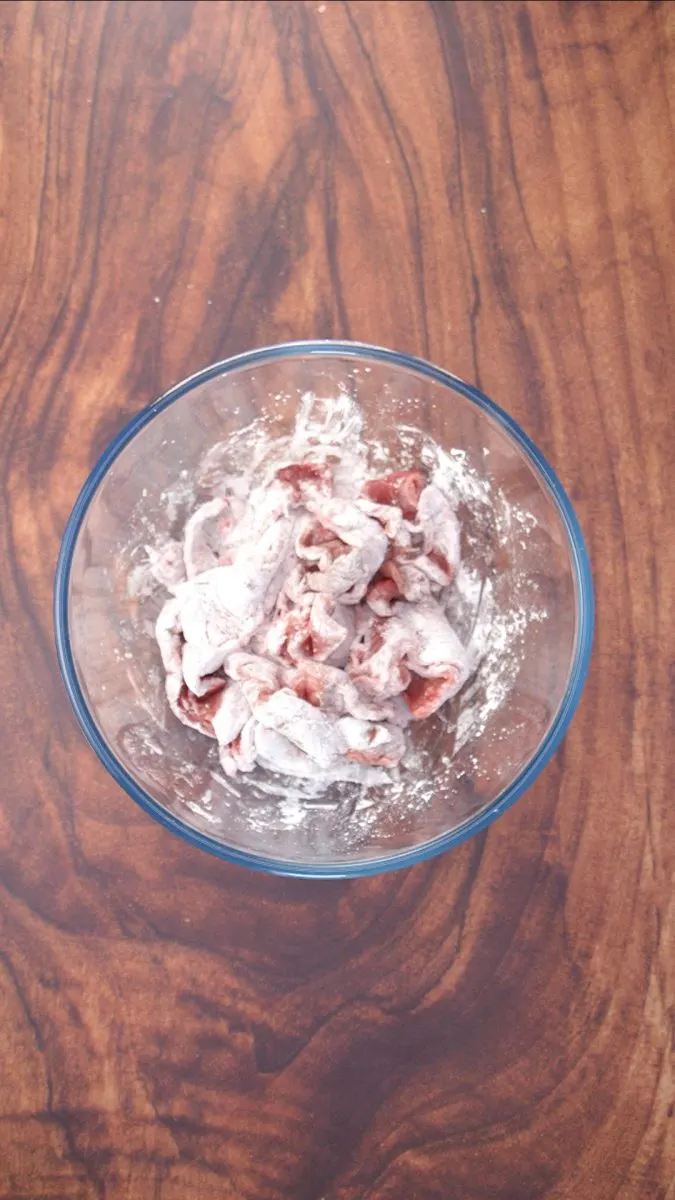 A bowl filled with strips of beef coated with corn starch - Hostess At Heart