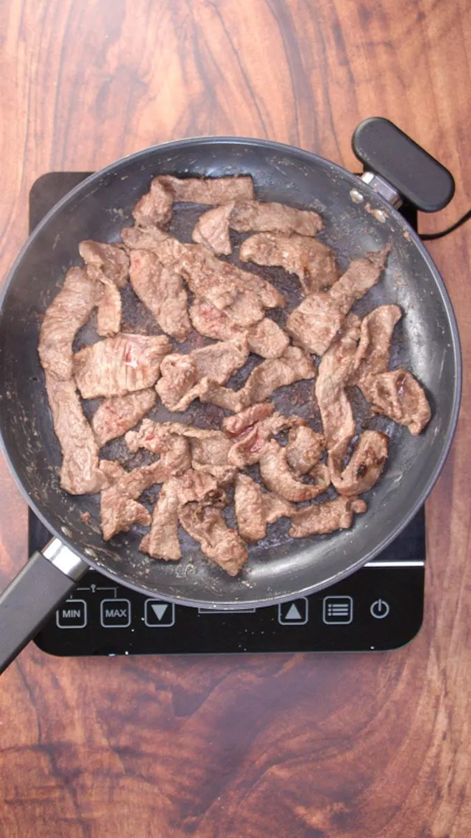 Strips of beef browning in a skillet - Hostess At Heart