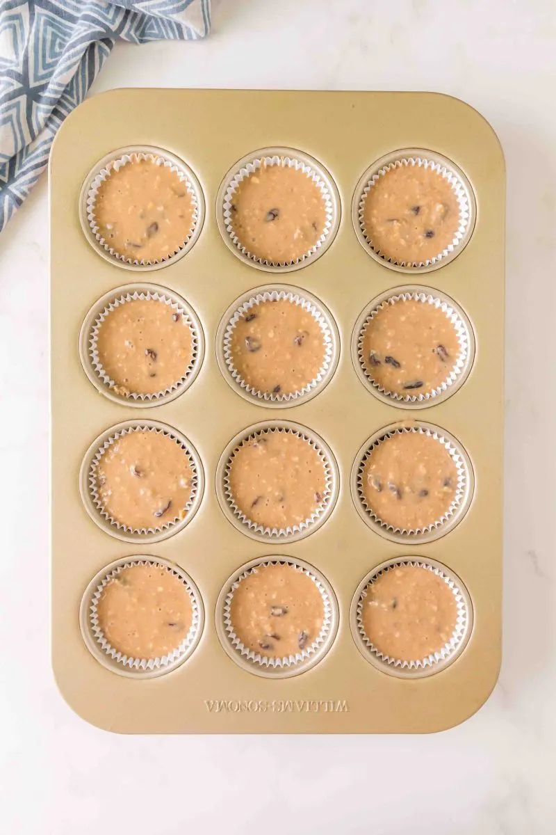 Top down view of a muffin pan filled with raisin oatmeal muffin batter - Hostess At Heart