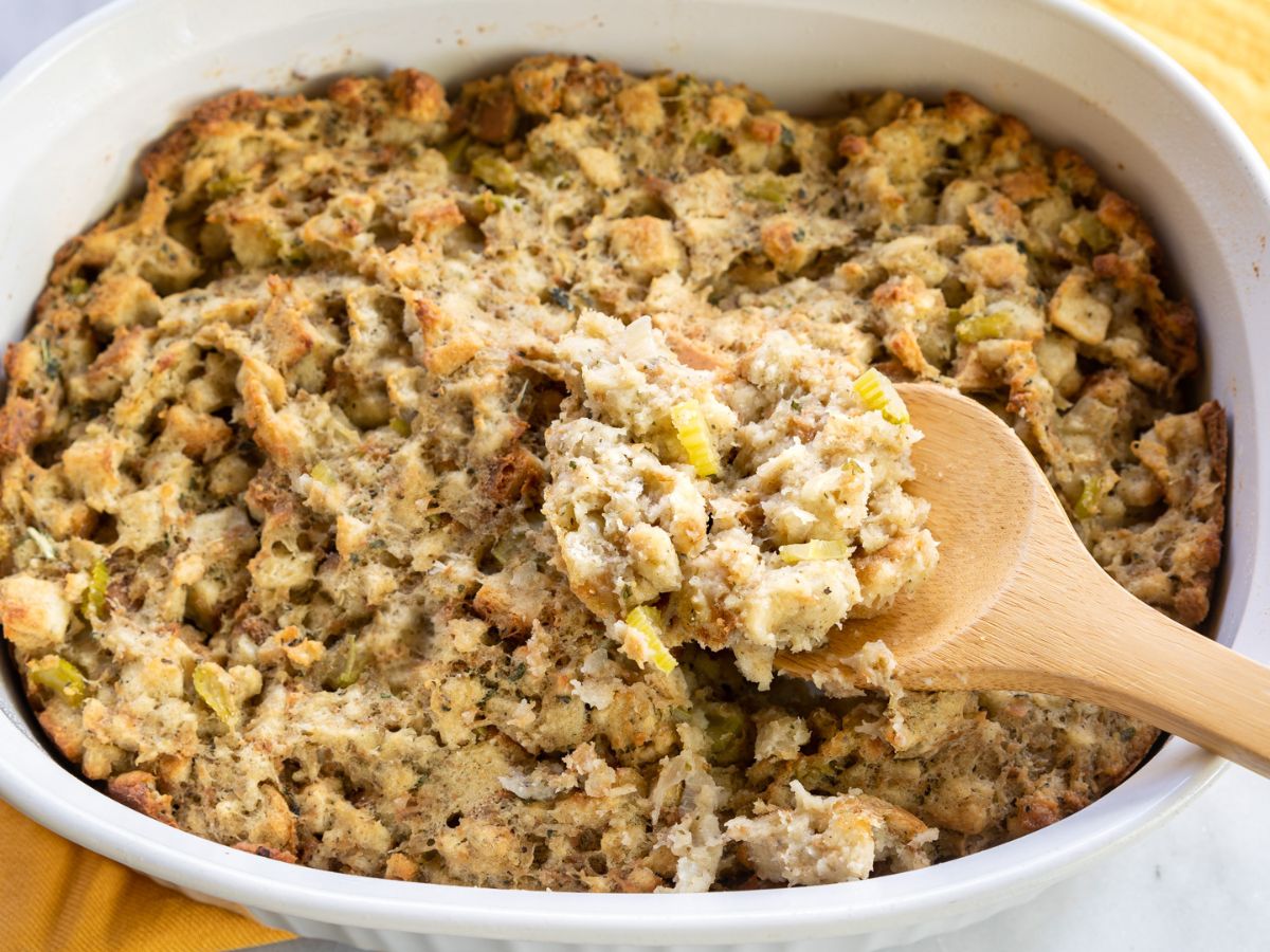 A serving spoon lifting a serving of oven- baked Thanksgiving Dressing. Hostess At Heart