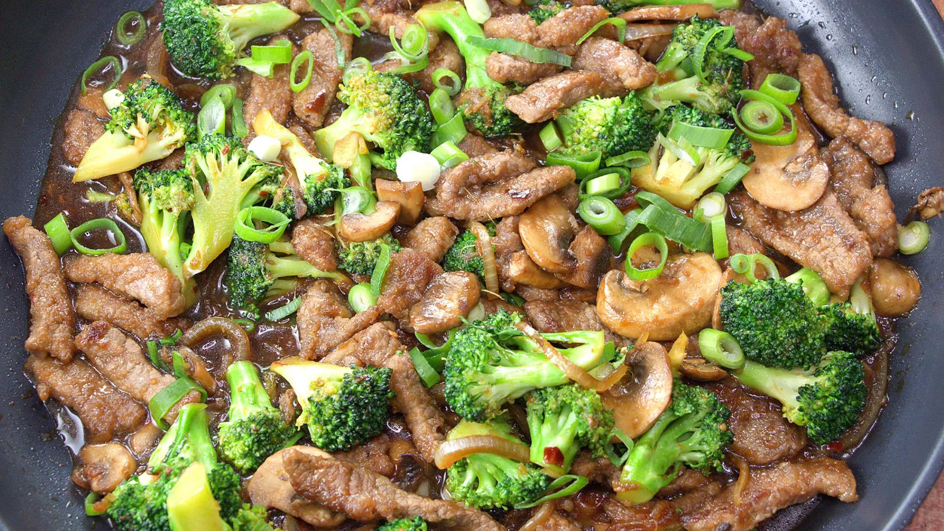 Beef and Broccoli Stir Fry with mushrooms and green onions in skillet. 