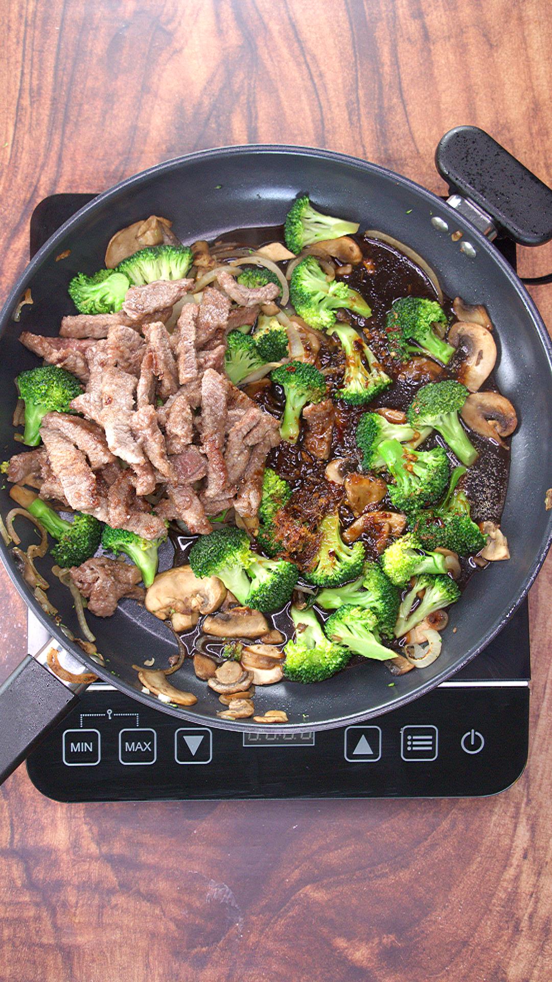 Top down view of a skillet filled with strips of steak and stir-fry sauce in an Asian sauce.