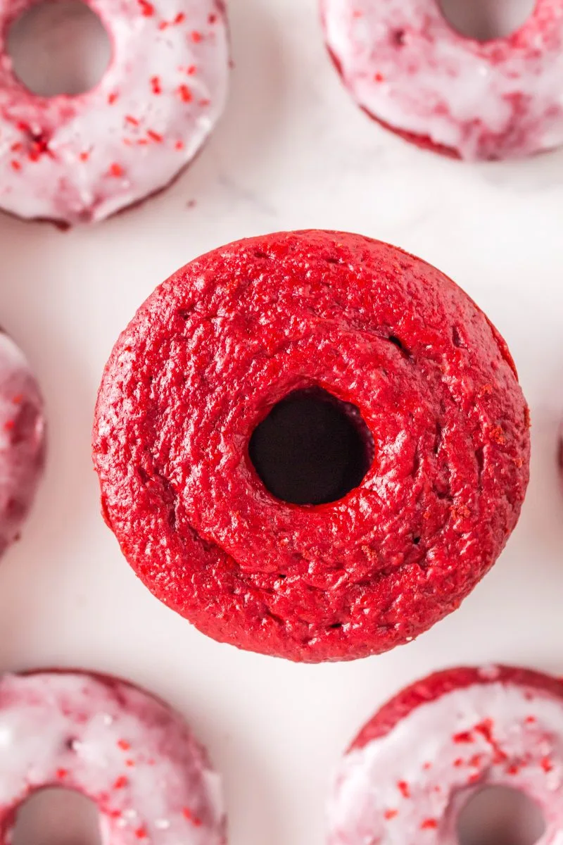 Close up of unglazed donut with glazed donuts in the background.