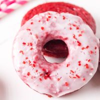 Top down view of a red velvet donut dipped in glaze and sprinkled with red and white sugar - Hostess At Heart