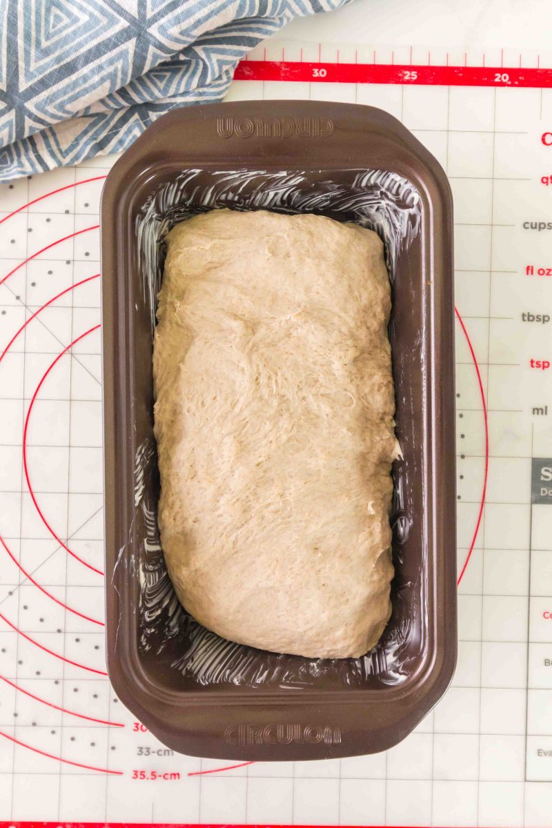 Shaping the dough to fit in the pan. Dough rests in pan on a cutting board with towel in the background.